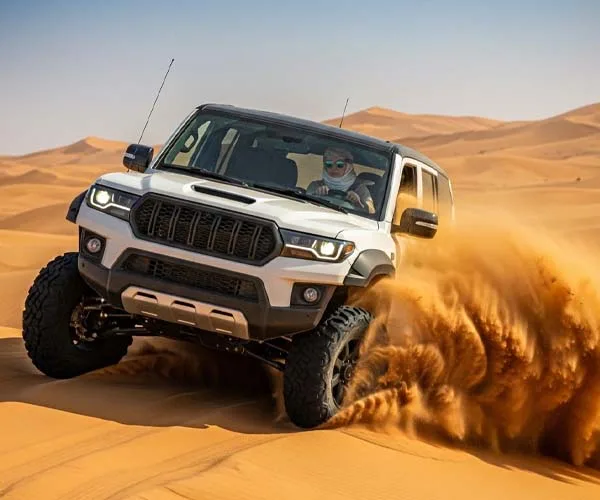 A white 4x4 SUV drifting through high sand dunes in the Dubai desert, kicking up a large cloud of sand.